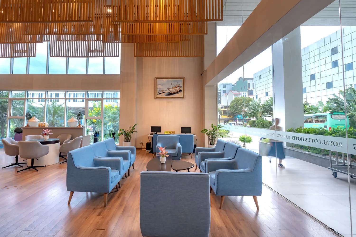 Helle Hotellobby mit blauen Sesseln, Holzboden und Glasfront zur Straße